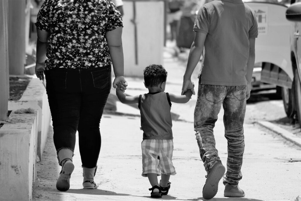A family of three walks hand-in-hand on a sunny day in Santiago, Dominican Republic.